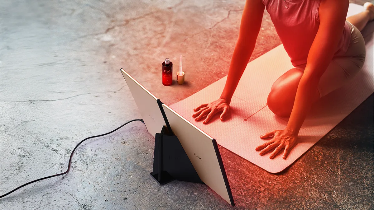 Woman using FAQ DUAL near infrared therapy light while doing yoga for faster recovery